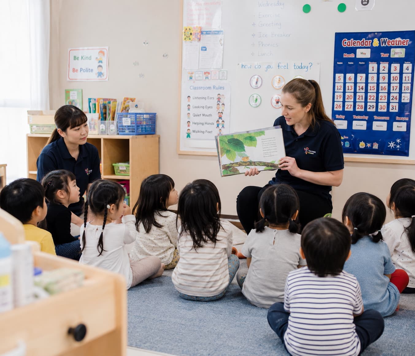 園で先生が子どもたちに絵本を読み聞かせている様子